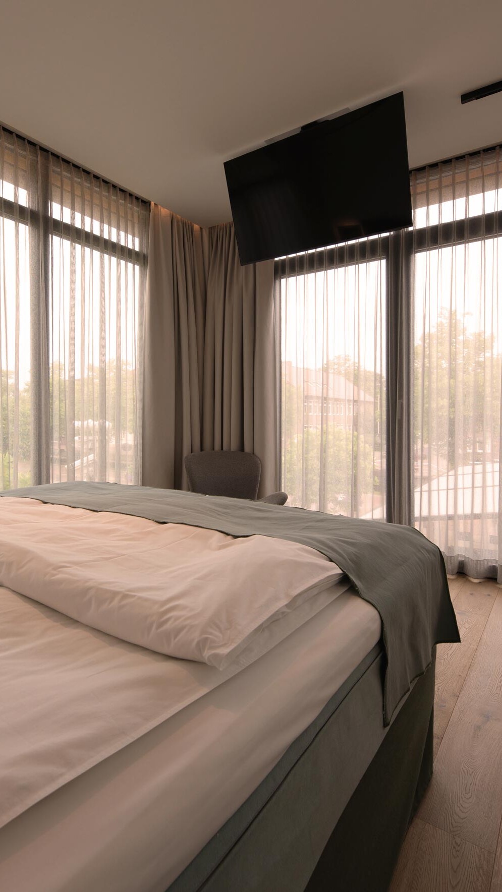 Lichtdurchflutetes Zimmer mit großem Bett und TV